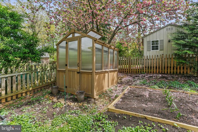 view of yard featuring an outdoor structure, a fenced backyard, and a greenhouse