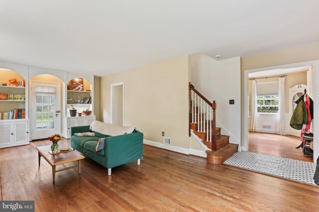 living area featuring stairs, baseboards, visible vents, and wood finished floors