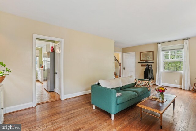 living room with stairs, baseboards, and light wood-type flooring
