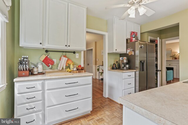 kitchen with stainless steel fridge, light countertops, white cabinetry, and ceiling fan