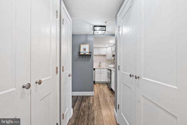 corridor featuring a sink and dark wood-style floors