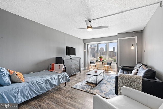 living room featuring a textured ceiling, wood finished floors, and ceiling fan