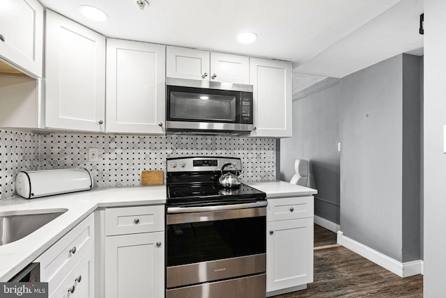 kitchen featuring baseboards, dark wood finished floors, white cabinetry, tasteful backsplash, and appliances with stainless steel finishes