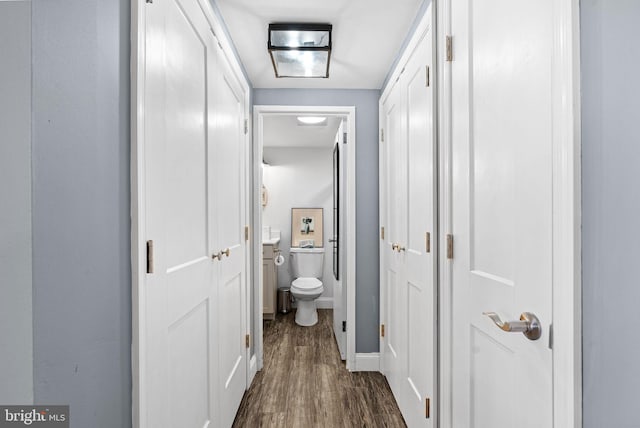 bathroom with toilet, baseboards, and wood finished floors