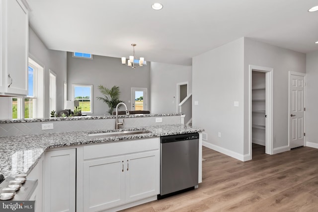 kitchen featuring light stone counters, a sink, dishwasher, white cabinetry, and tasteful backsplash