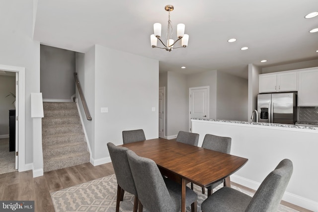 dining area featuring light wood-type flooring, stairs, baseboards, a notable chandelier, and recessed lighting