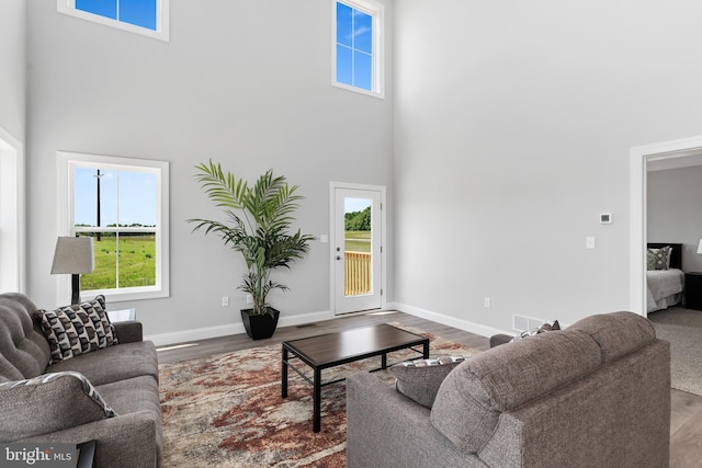 living area featuring a healthy amount of sunlight, a high ceiling, wood finished floors, and visible vents