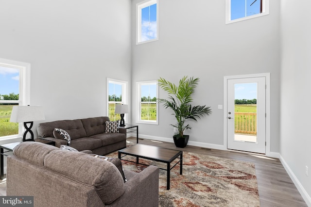 living room featuring baseboards, a high ceiling, wood finished floors, and visible vents