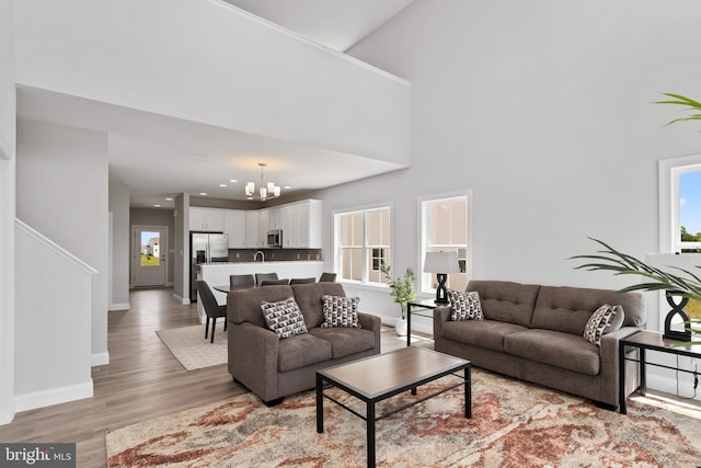 living area featuring baseboards, recessed lighting, light wood-style flooring, and a notable chandelier