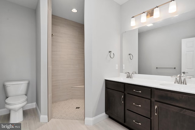 bathroom with a sink, baseboards, toilet, and double vanity