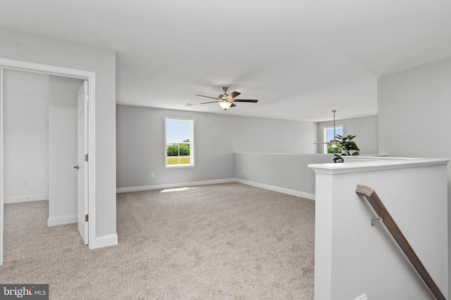 carpeted spare room featuring baseboards and ceiling fan