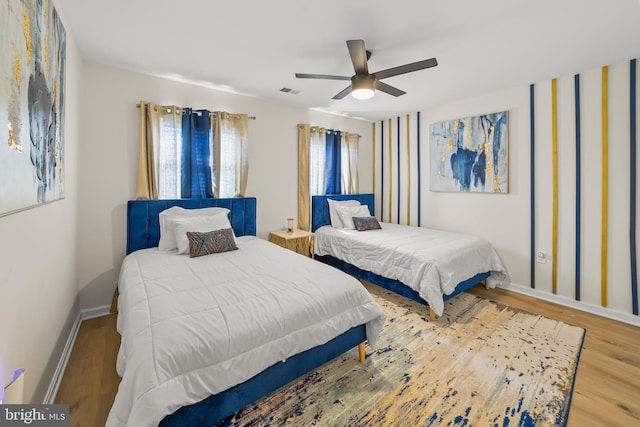 bedroom with visible vents, ceiling fan, wood finished floors, and baseboards