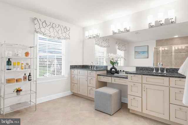 full bathroom with double vanity, baseboards, a sink, and a stall shower