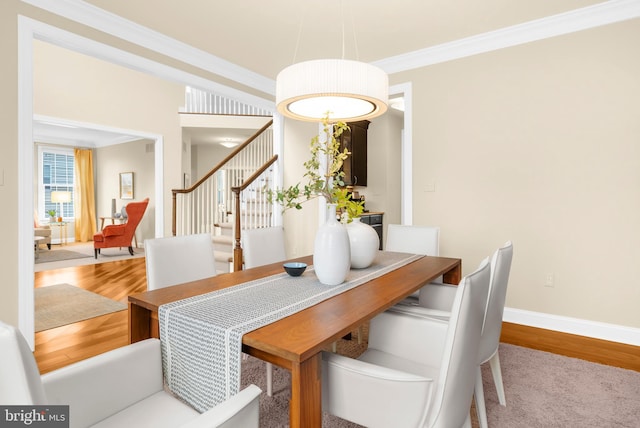 dining room featuring crown molding, baseboards, stairs, and wood finished floors