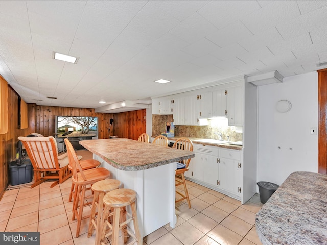 24 Keeler Ave, Stevens, PA 17578 - kitchen with wooden walls, light countertops, light tile patterned floors, a breakfast bar, and white cabinets