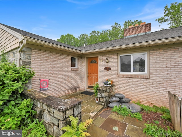 24 Keeler Ave, Stevens, PA 17578 - view of exterior entry with brick siding, a chimney, and roof with shingles