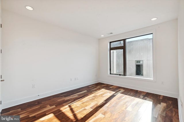 empty room with baseboards, dark wood-type flooring, and recessed lighting
