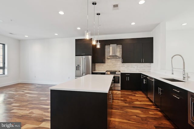 kitchen with stainless steel appliances, wall chimney exhaust hood, a sink, dark wood-style floors, and decorative backsplash