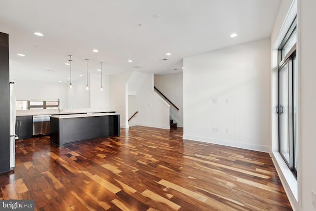 unfurnished living room with dark wood finished floors, recessed lighting, stairs, and baseboards