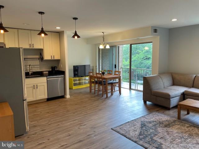 living area with visible vents, recessed lighting, wood finished floors, and a notable chandelier