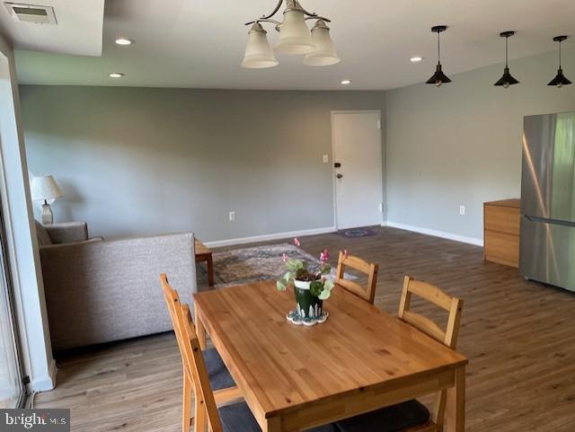 dining room with visible vents, wood finished floors, baseboards, recessed lighting, and a notable chandelier