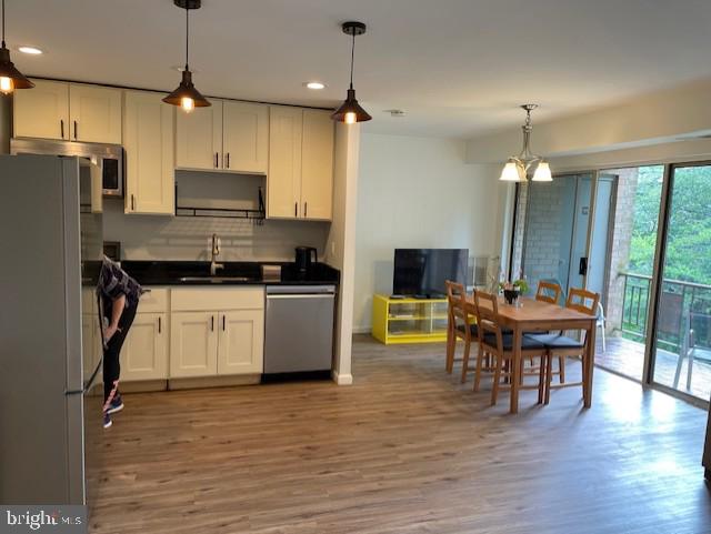 kitchen with dark countertops, recessed lighting, white cabinets, a sink, and stainless steel appliances