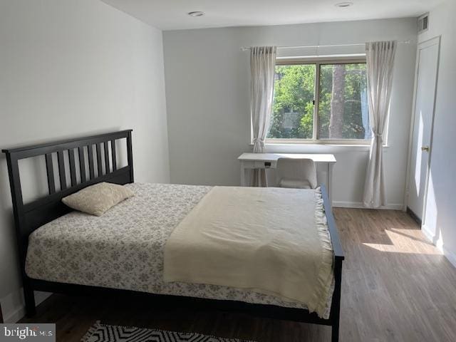 bedroom with visible vents, baseboards, and wood finished floors