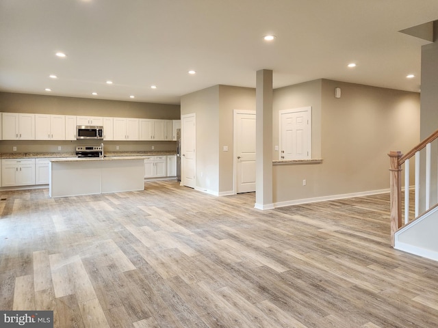 kitchen featuring appliances with stainless steel finishes, baseboards, white cabinets, open floor plan, and recessed lighting
