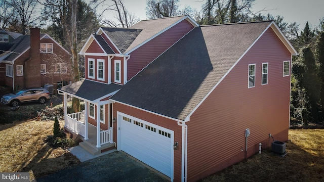 view of front of house featuring central AC, driveway, a shingled roof, and an attached garage