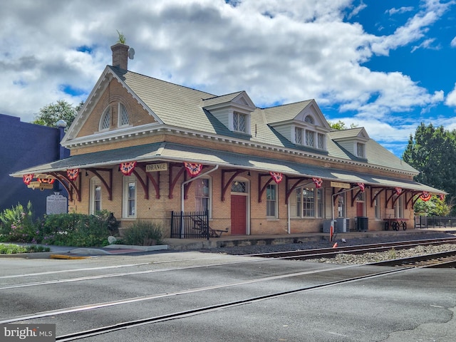view of front facade with covered porch, a chimney, and brick siding