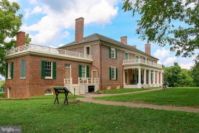 rear view of property featuring brick siding, a yard, and a chimney