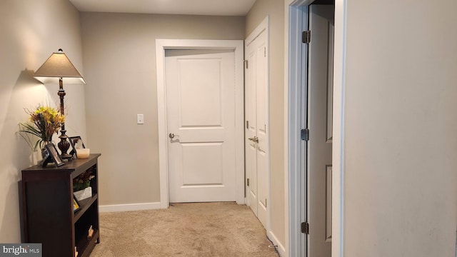 hall with baseboards and light colored carpet
