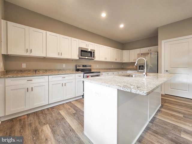 kitchen featuring a sink, wood finished floors, white cabinets, and stainless steel appliances