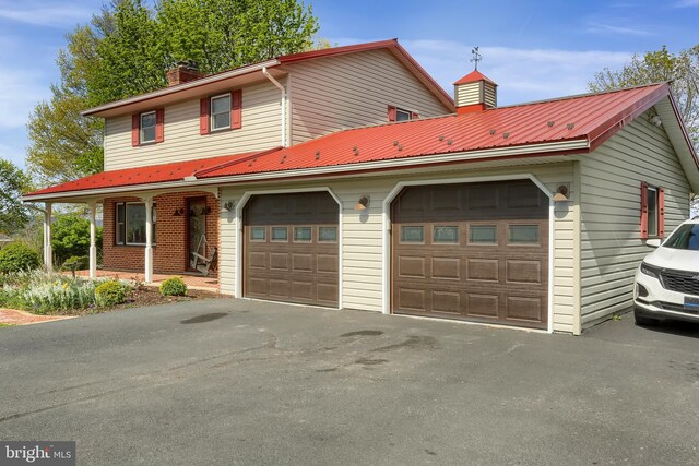 traditional-style home featuring metal roof, a chimney, and covered porch