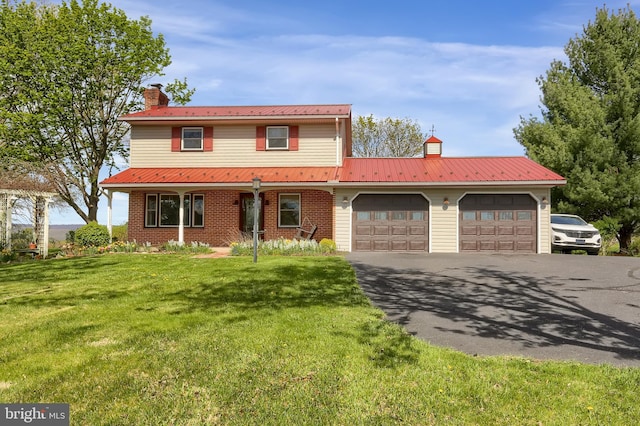 traditional-style house featuring a garage, a front lawn, a chimney, and aphalt driveway