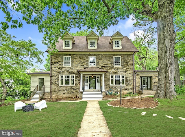 colonial house featuring stone siding and a front lawn