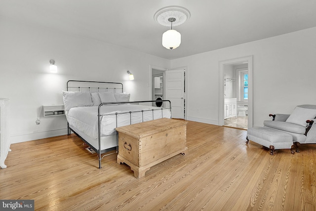 bedroom featuring light wood-style flooring, baseboards, and ensuite bathroom