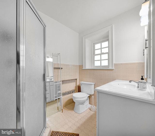 bathroom with radiator, tile walls, wainscoting, vanity, and toilet