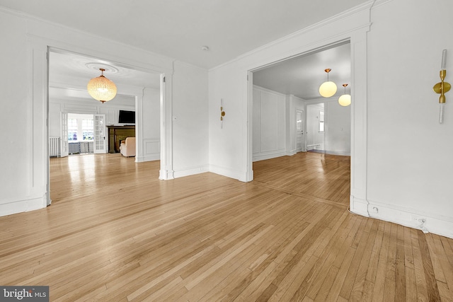 unfurnished room with light wood-style floors, ornamental molding, radiator heating unit, and baseboards