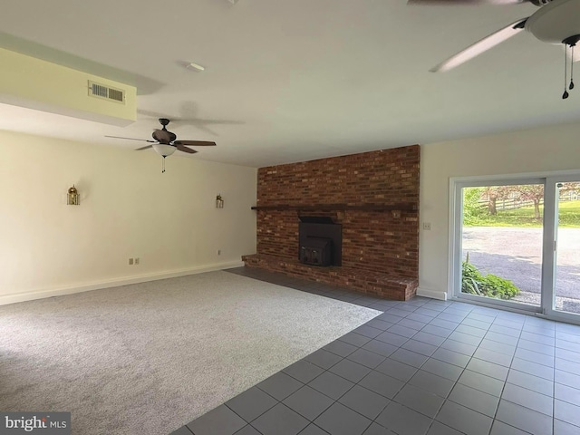 unfurnished living room featuring ceiling fan, tile patterned floors, baseboards, carpet, and a wood stove