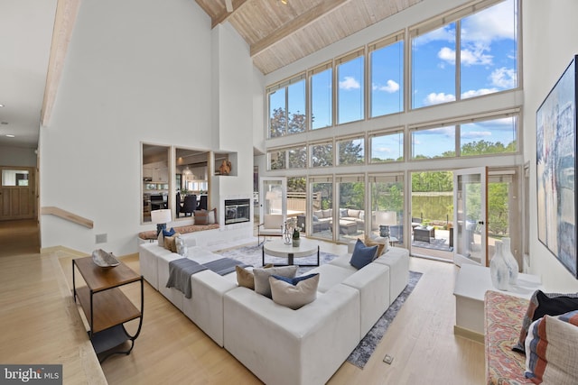 living room with beam ceiling, high vaulted ceiling, a healthy amount of sunlight, and wooden ceiling