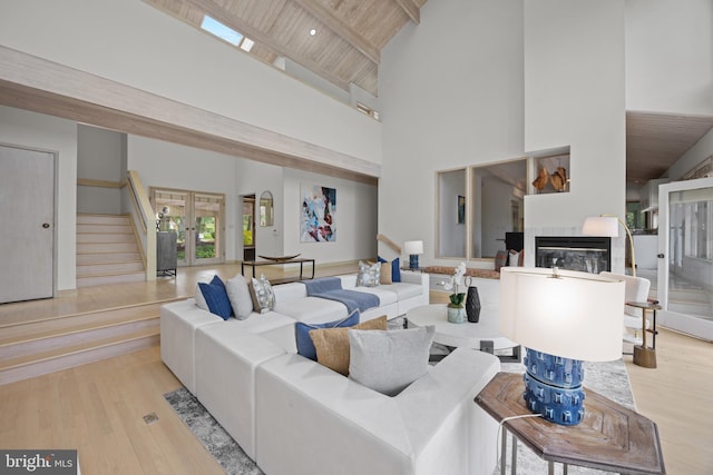 living area featuring high vaulted ceiling, a glass covered fireplace, wood ceiling, french doors, and wood finished floors