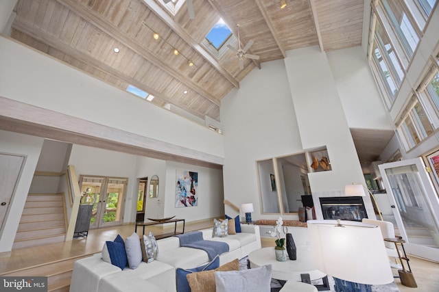living area with a tile fireplace, wooden ceiling, french doors, and high vaulted ceiling