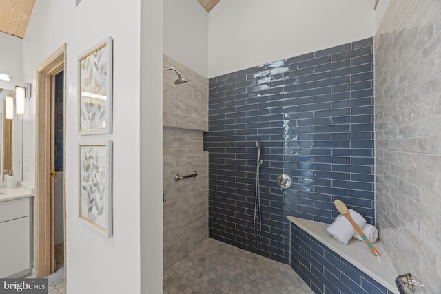 full bath with a tile shower and vanity