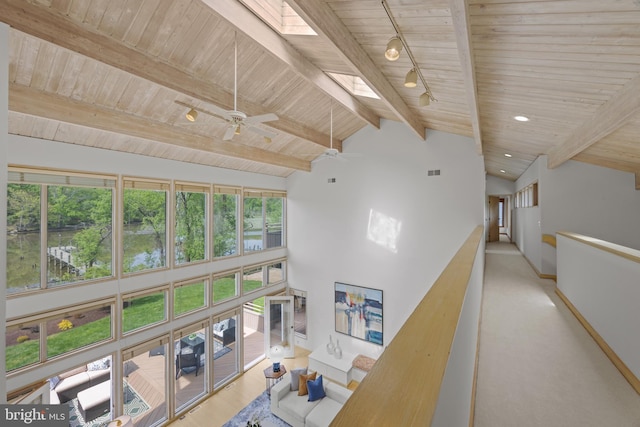 corridor featuring track lighting, a wealth of natural light, lofted ceiling with skylight, and wooden ceiling
