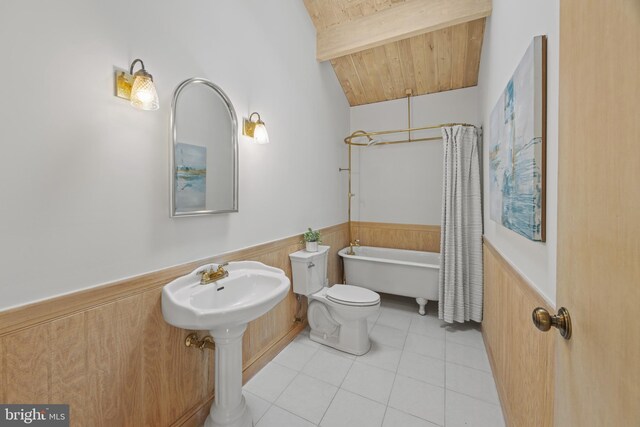 bathroom with lofted ceiling with beams, a bathtub, tile patterned floors, toilet, and wainscoting