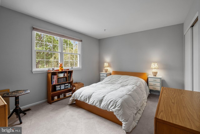 carpeted bedroom with a closet and baseboards