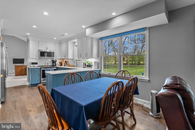 dining space featuring baseboards, hardwood / wood-style floors, and recessed lighting