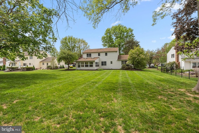 rear view of property featuring a lawn and fence