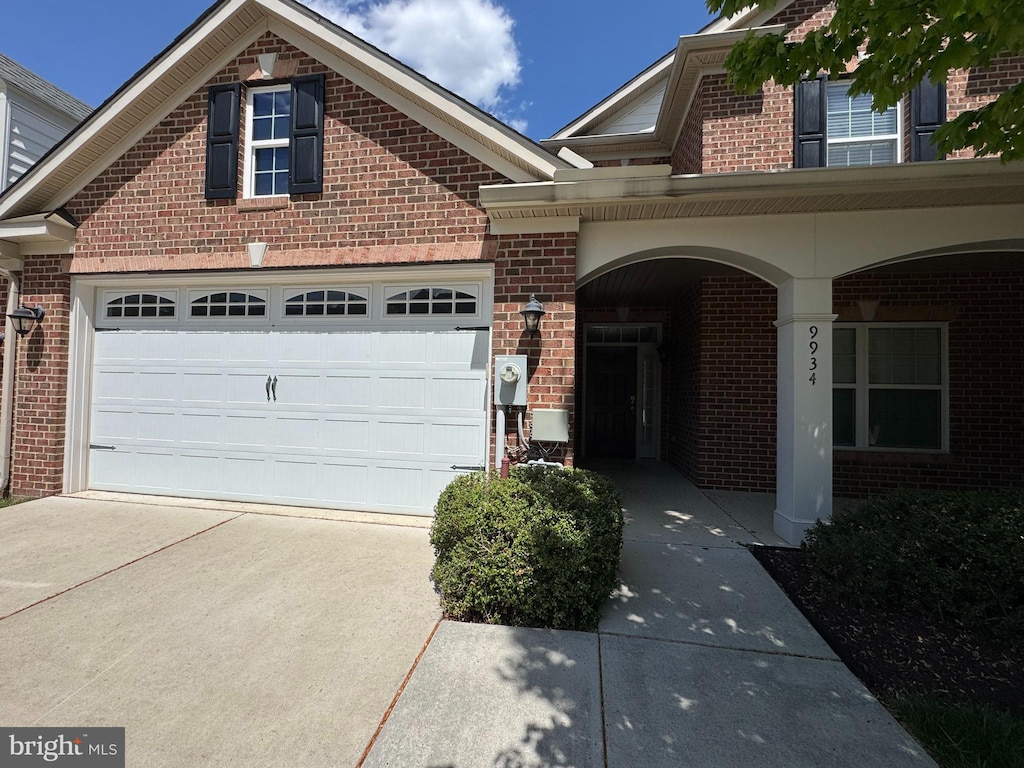 view of front facade featuring a garage, a porch, driveway, and brick siding